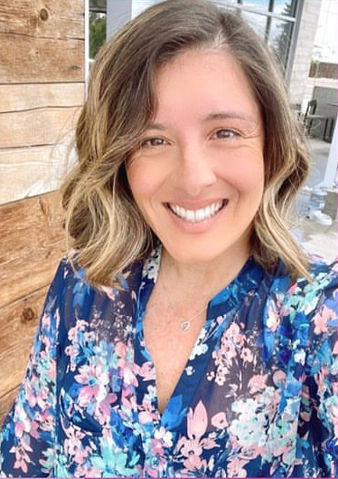 Alicia Roman, a fair skinned woman with brown blonde hair, in a floral top
