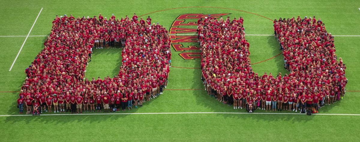 DU logo formed by students on lacrosse field.